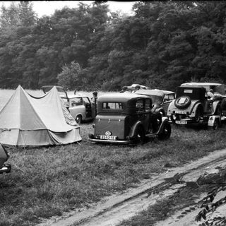 Vintage cars and tents at lakeside campsite.