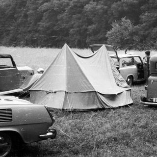 Vintage cars and tents at lakeside campsite.