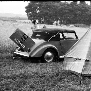 Vintage cars parked beside a canvas tent.
