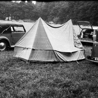 Vintage cars parked beside a canvas tent.
