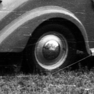 Vintage cars parked beside a canvas tent.
