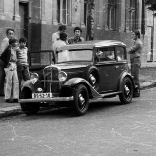 Vintage street scene with vintage cars and people in 1930s-40s.