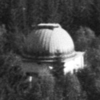 Isolated dome structure atop forested hill.