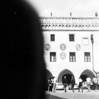 Historic building facade with arched entrance, cobblestone square.