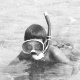 Children swimming and snorkeling in a large pool.