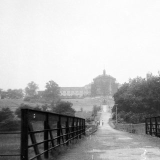 Historic building viewed through misty bridge.
