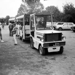 Small shuttle bus loading passengers in parking area.