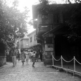 Narrow cobblestone street with people walking near historic buildings.