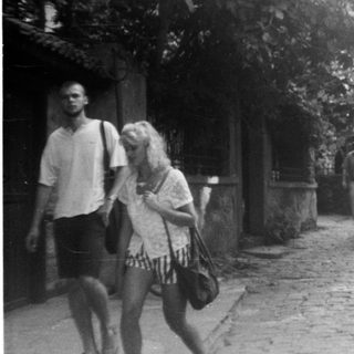 Narrow cobblestone street with people walking near historic buildings.