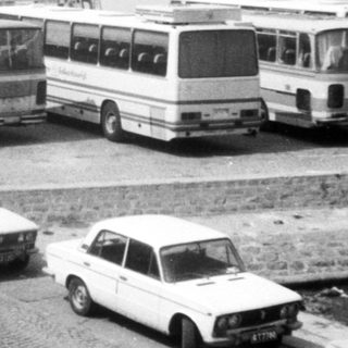 Bus terminal by coastal roadside with parked buses.