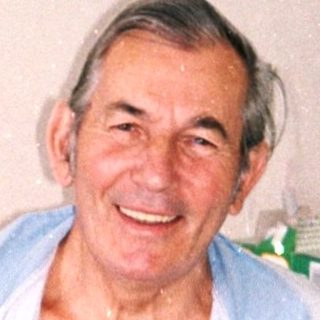 Smiling elderly man in hospital bed.