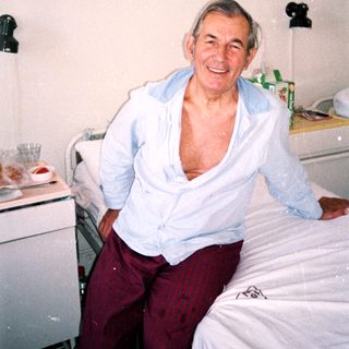 Smiling elderly man in hospital bed.