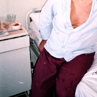 Smiling elderly man in hospital bed.