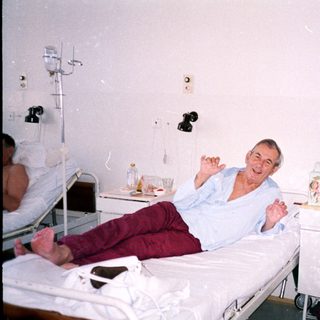 Hospital room with man smiling on bed.