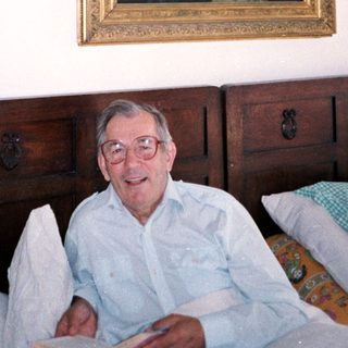 Man sitting on bed with religious painting above him.