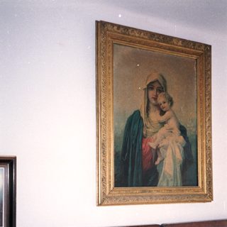 Man sitting on bed with religious painting above him.