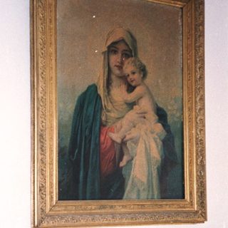 Man sitting on bed with religious painting above him.