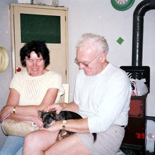 Two people holding and smiling with small dog.