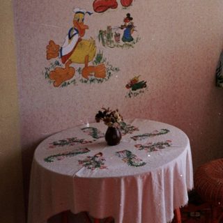 Vintage room with Disney characters mural, floral tablecloth, sewing machine.