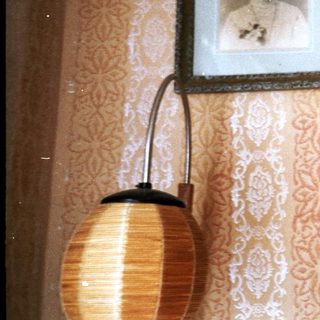 Vintage framed portraits on patterned wall with lamp.