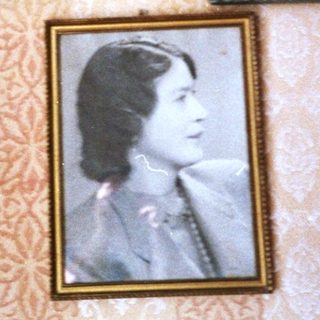Vintage framed portraits on patterned wall with lamp.