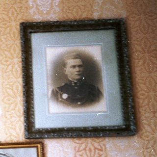 Vintage framed portraits on patterned wall with lamp.