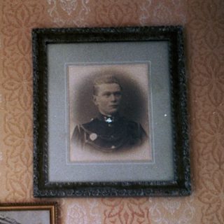 Vintage portraits in ornate frames on patterned wall.
