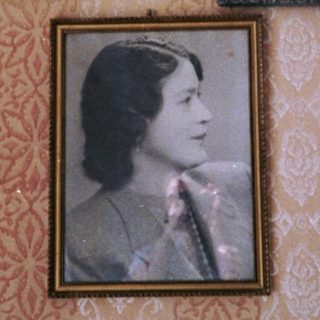 Vintage portraits in ornate frames on patterned wall.