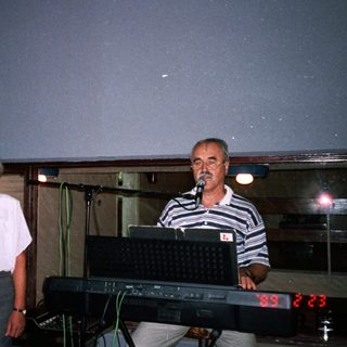 Three adults posing near a keyboard and digital clock.