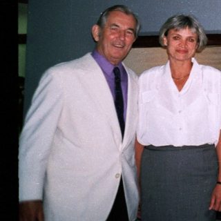 Three adults posing near a keyboard and digital clock.