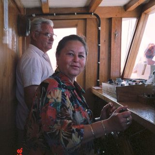 Two people in a wooden cabin, one cooking.