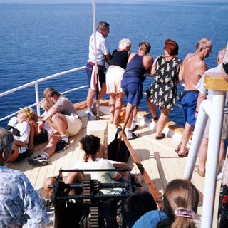 Group enjoying time on cruise ship deck by ocean.