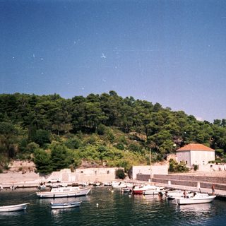 Coastal village with boats, historic stone buildings, and sea.