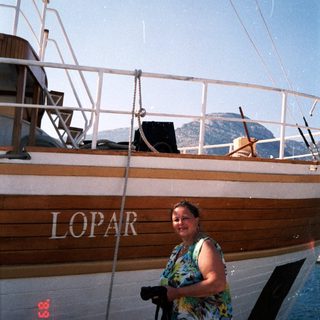 Woman standing beside wooden boat named "Lopar."