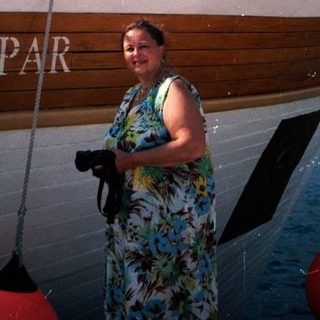 Woman standing beside wooden boat named "Lopar."