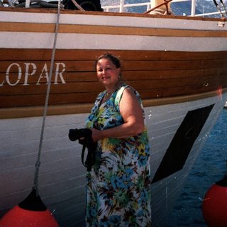 Woman standing beside wooden boat named "Lopar."
