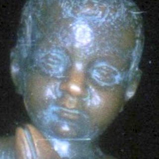 Bronze statue of child playing flute on coconut.