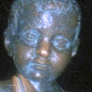 Bronze statue of child playing flute atop globe.