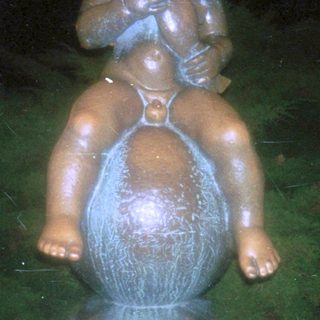 Bronze statue of child playing flute atop globe.