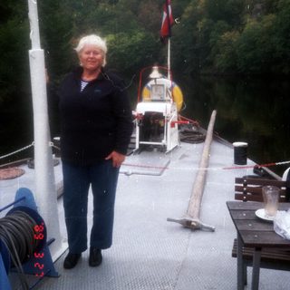 Woman standing on a small boat near a docked ferry.