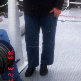 Woman standing on a small boat near a docked ferry.