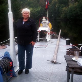 Woman standing on a small boat near a docked ferry.