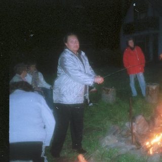 People roasting food over a nighttime campfire.