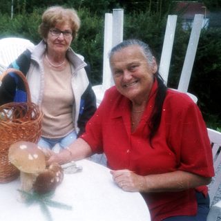 Two people smiling with foraged mushrooms on table.