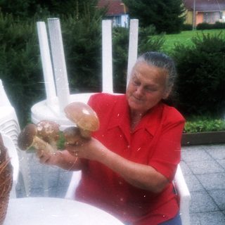 Woman tossing bread rolls outdoors.