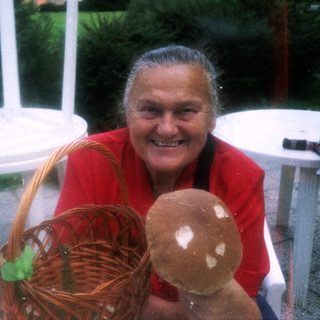 Happy woman holding basket with mushroom outdoors.