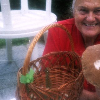 Happy woman holding basket with mushroom outdoors.