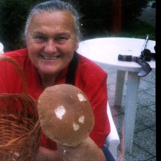 Happy woman holding basket with mushroom outdoors.