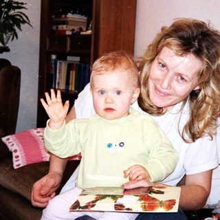Mother and baby playing with picture book indoors.