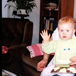 Mother and baby playing with picture book indoors.